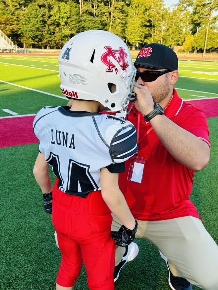 480554155_1005513824968795_5325946667174525066_n Coach fixing football player's helmet
